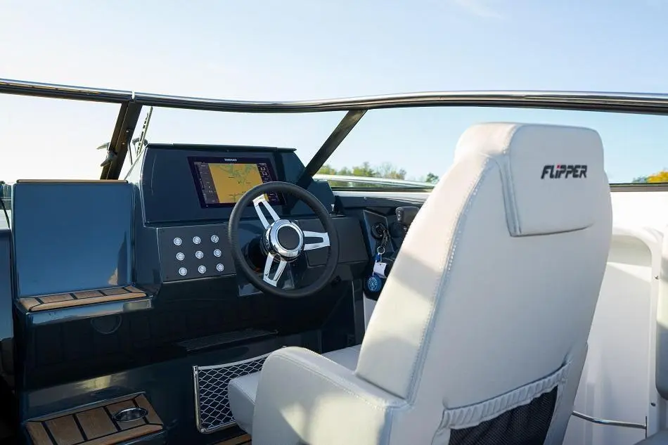 Interior of a modern boat cockpit featuring a steering wheel, control panel, and a seat labelled "FLIPPER.